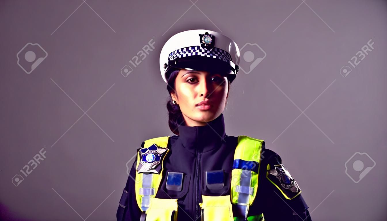 Retrato de estudio de una joven policía seria contra un fondo liso
