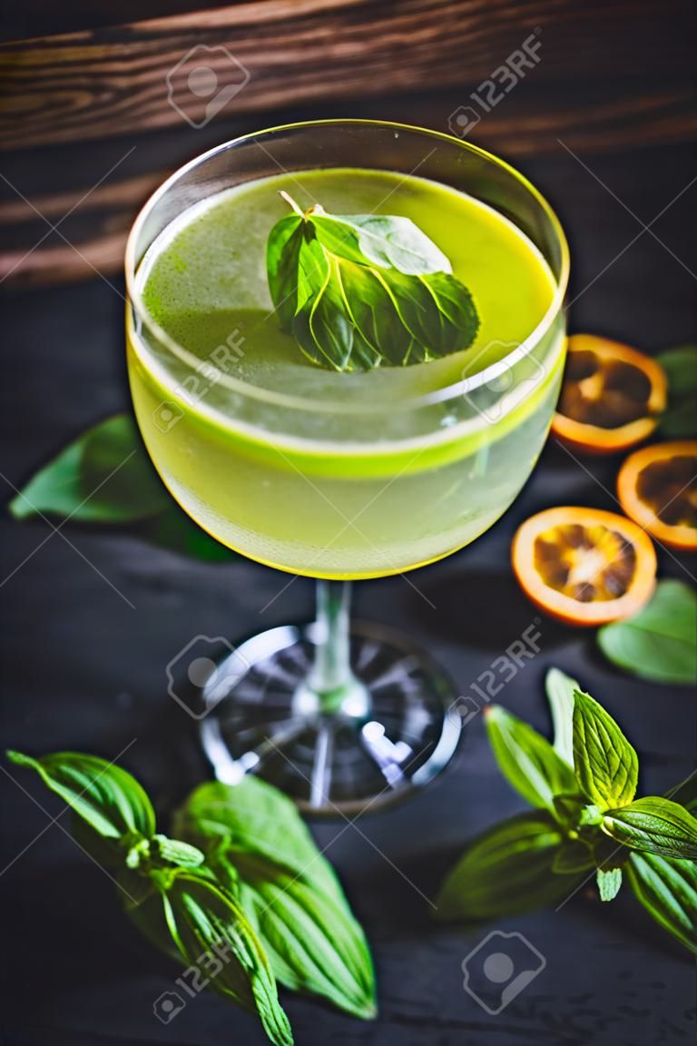 A carbonated cocktail with a mint leaf in a glass.