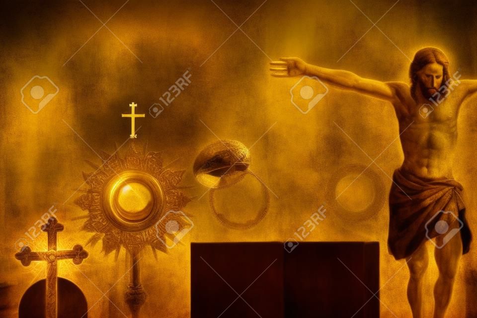 Simboli della religione cattolica. La Croce, l'ostensorio, la figura di Gesù, la Sacra Bibbia e il calice d'oro sul tavolo in legno rustico.