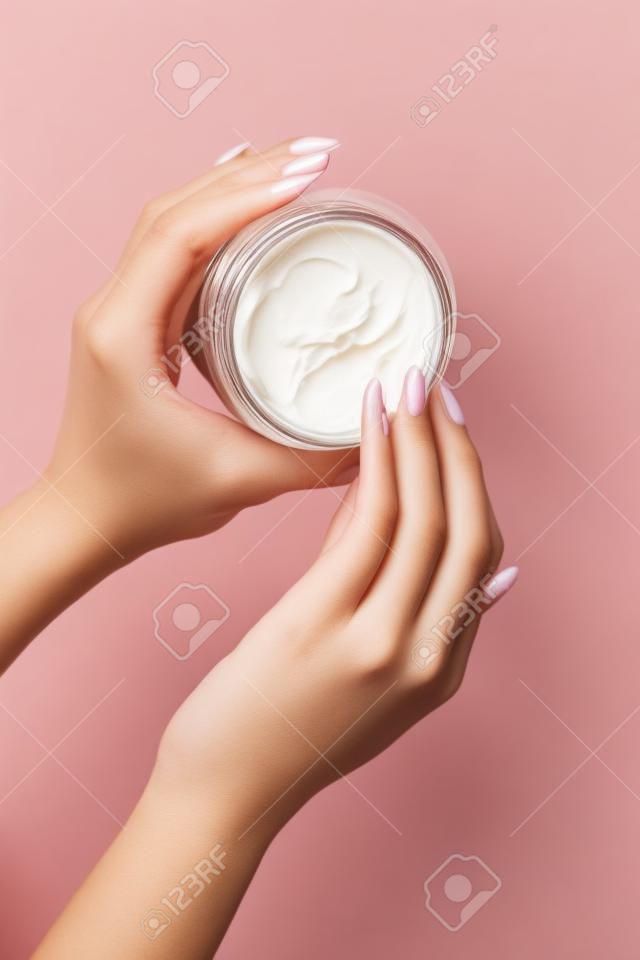 Bovenaanzicht, close-up van vrouwelijke handen. Meisje picks up crème uit een pot voor huidverzorging met haar vinger