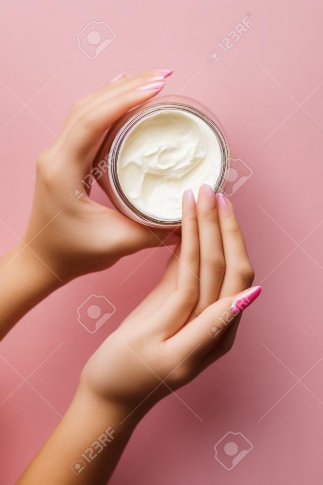 Bovenaanzicht, close-up van vrouwelijke handen. Meisje picks up crème uit een pot voor huidverzorging met haar vinger