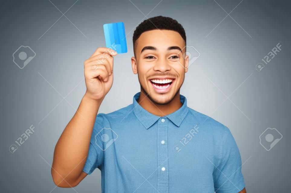 Feliz el hombre joven que muestra su tarjeta de crédito
