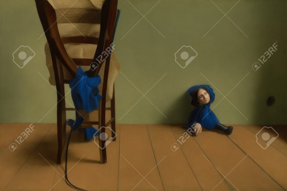 Jovem mulher amarrada a uma cadeira em um quarto vazio