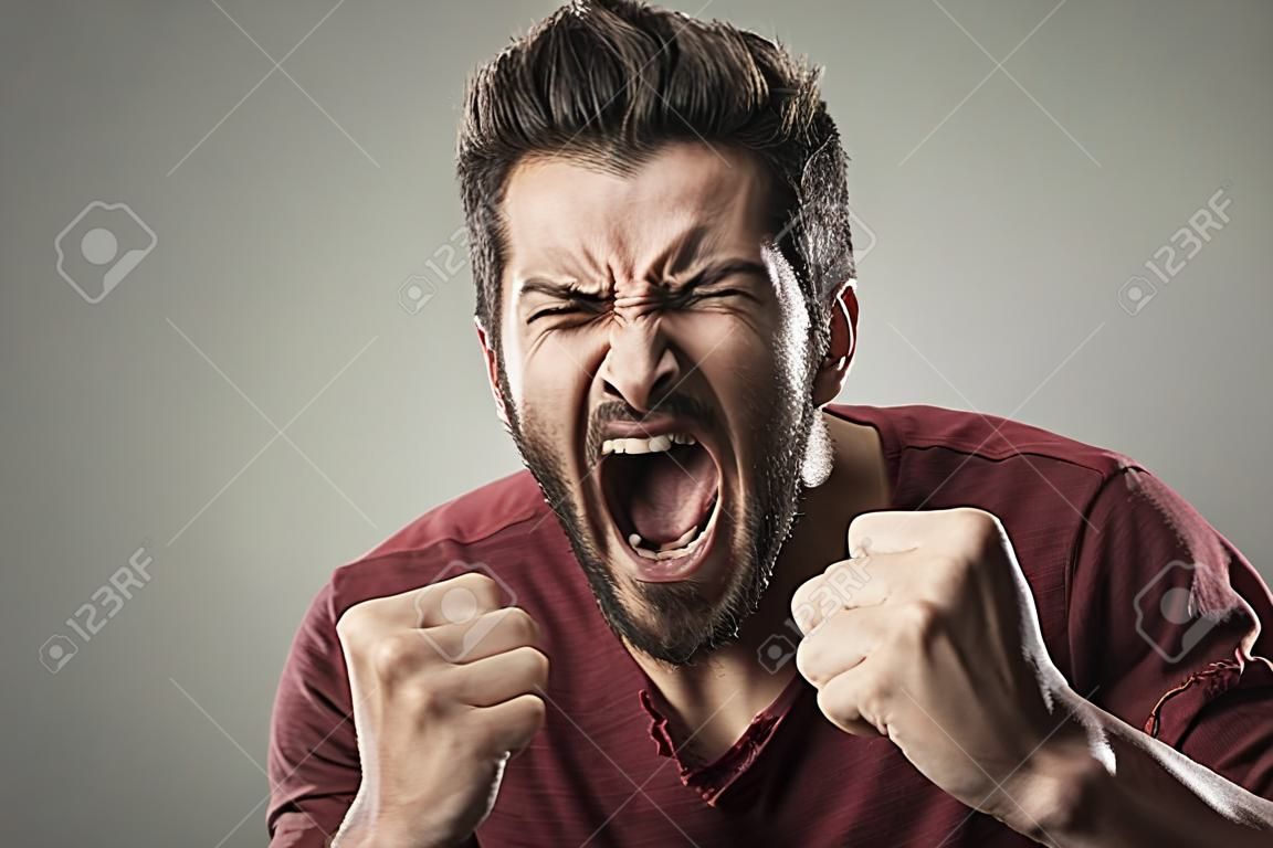 Hombre agresivo enojado gritando en voz alta con expresión feroz
