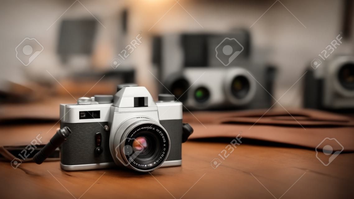 Fotógrafo profissional que trabalha com um computador na agência de comunicação e câmera vintage em primeiro plano
