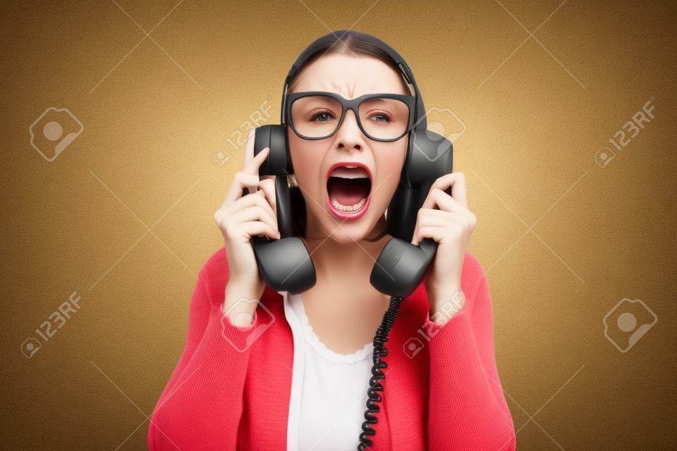 Woman holding two telephone receivers and shouting, she is stressed and angry