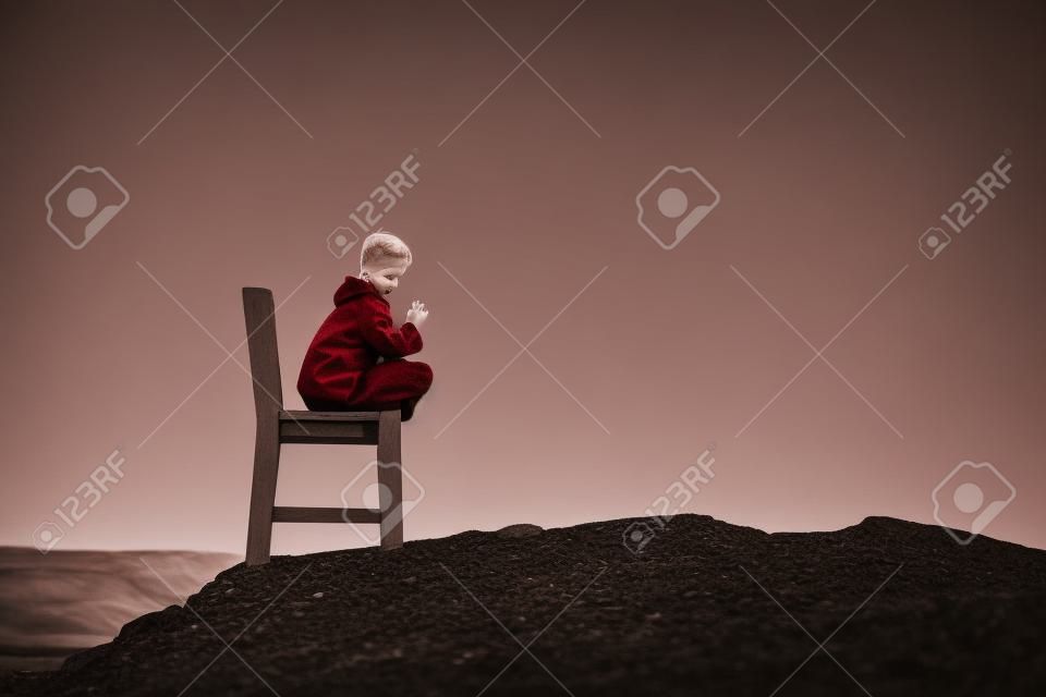 Girl on a red wooden chair on a empty stony landscape in Iceland. Toned.