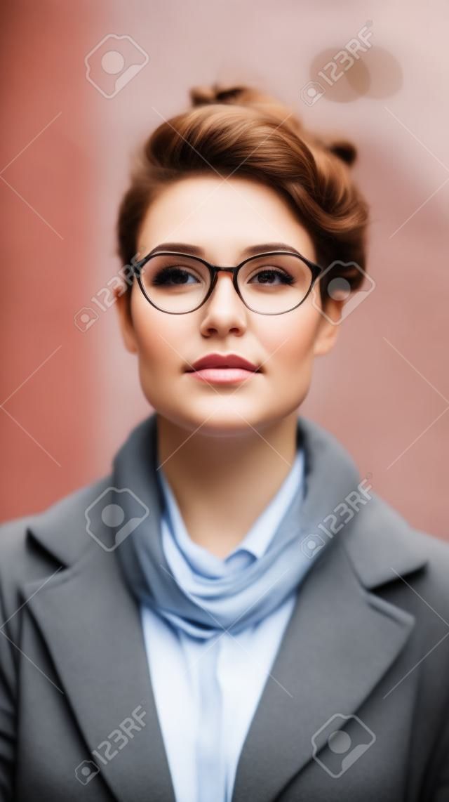 Portrait of a beautiful young woman with glasses on the street.