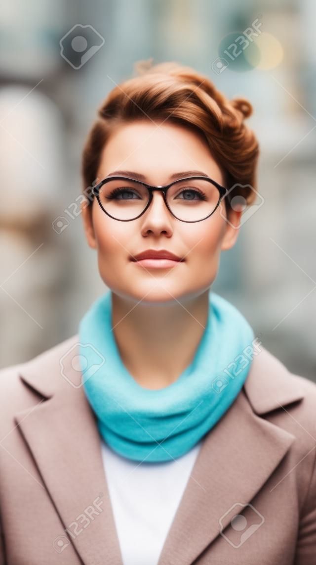 Portret van een mooie jonge vrouw met een bril op straat.