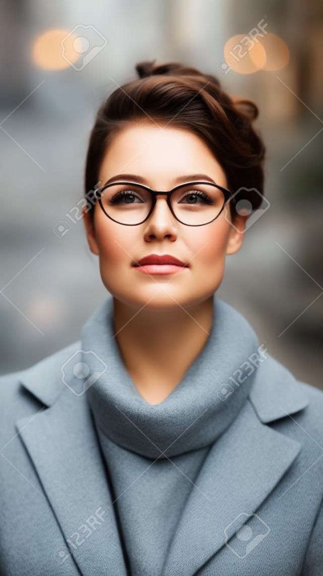 Portret van een mooie jonge vrouw met een bril op straat.