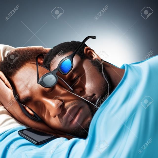 A black man is sleeping with glasses, a phone is lying next to him. Businessman daily routine