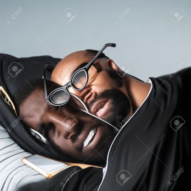 흑인 남자가 안경을 쓰고 자고 있고 그 옆에는 전화기가 놓여 있습니다. 사업가 일상