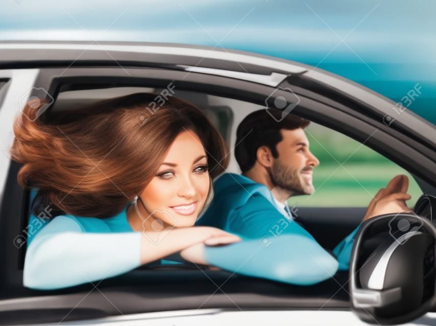 Kobieta wygląda przez okno samochodu, jej włosy powiewają na wietrze. mąż jeździ