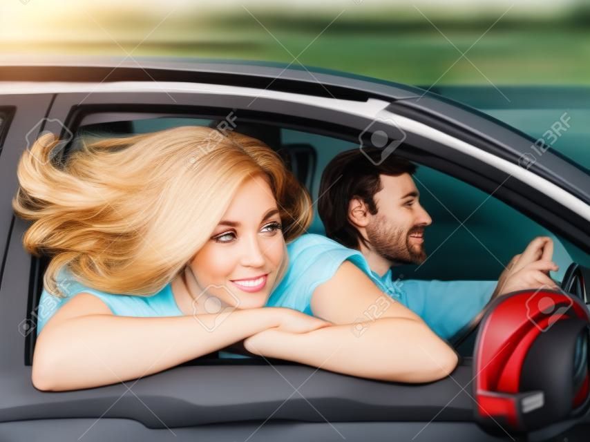 een vrouw kijkt uit een auto raam, haar haar fladderend in de wind. man rijden