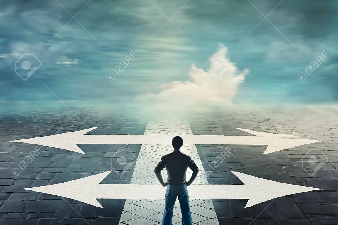 Confident man, hands on hips, stands in front of a crossroad with road split in three different ways as arrows. Choosing the correct pathway between left, right and front. Difficult decision concept.