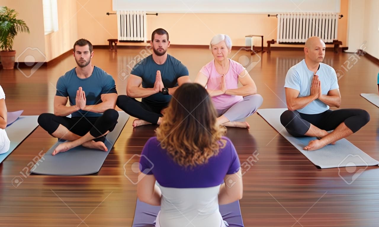 Konditionstrainer geben Gruppe Yoga-Anweisungen in ein Fitness-Studio