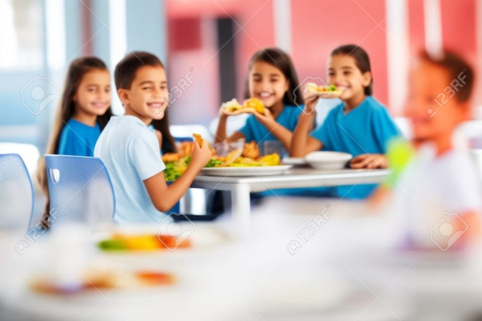 Grupo de niños como amigos almorzando en la cafetería de la escuela
