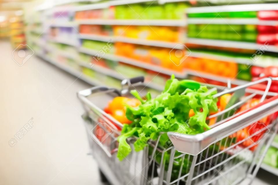 Fresh vegetables and other food in the shopping cart in the supermarket