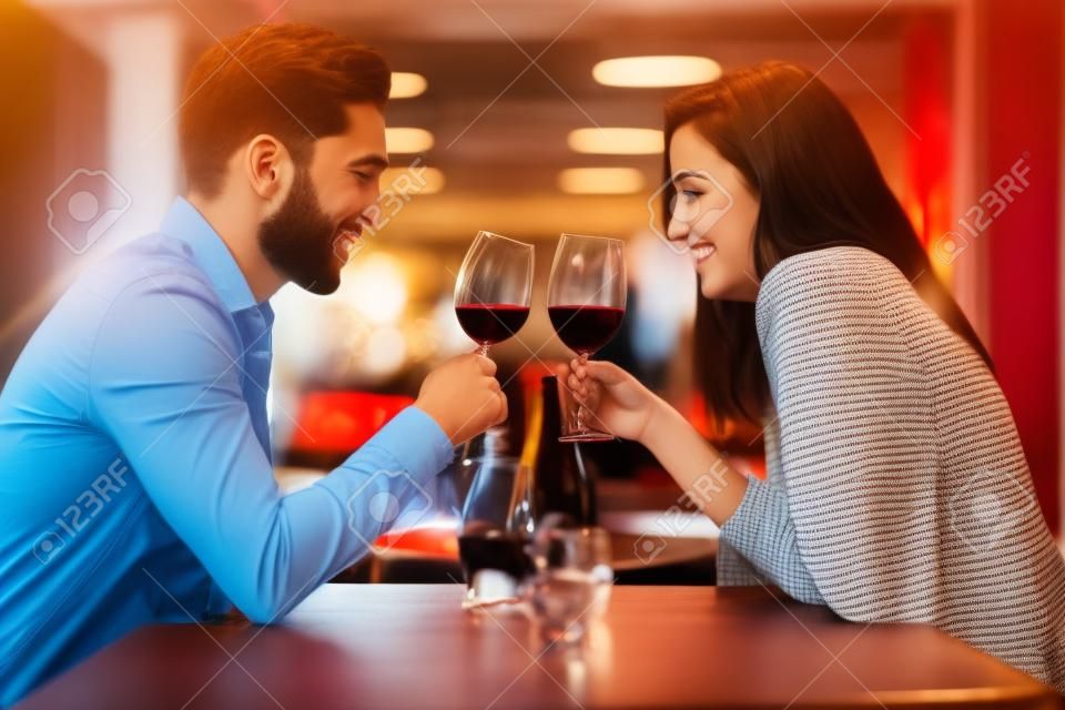 Zakochana młoda para spotyka się w restauracji, pijąc kieliszek czerwonego wina