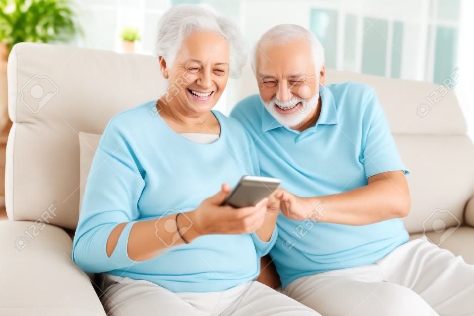 스마트폰을 사용하는 노인 부부는 재미있는 비디오 채팅을 하거나 문자 메시지를 읽습니다.