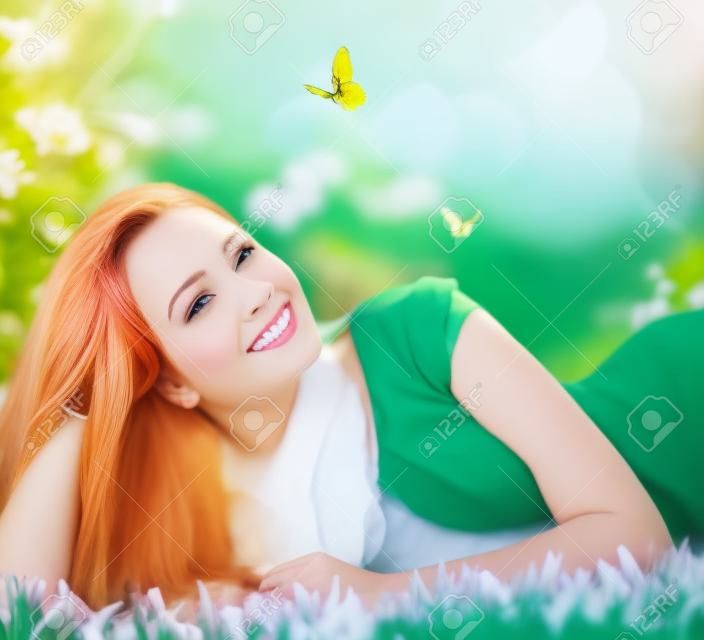 春季美容美麗的女孩躺在綠色的草地上戶外