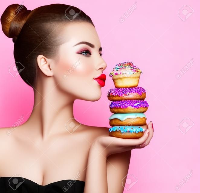 美容ファッション モデルの女の子のお菓子とカラフルなドーナツを撮影