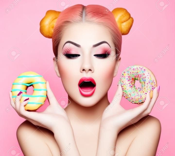 Красота мода модель девушки принимая сладости и красочные пончики