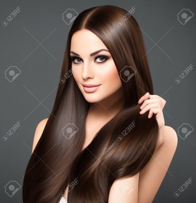 Bella donna bruna di toccare i suoi lunghi capelli lisci lucido