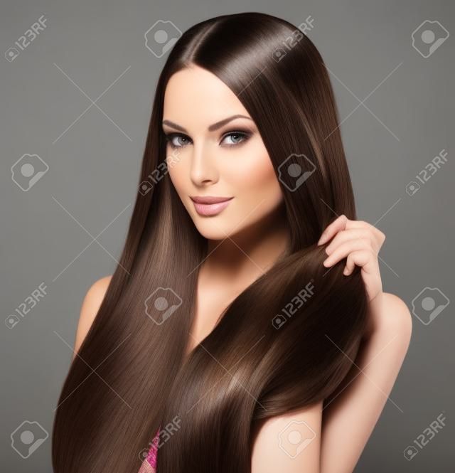 Bella donna bruna di toccare i suoi lunghi capelli lisci lucido