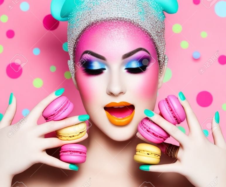 美女模特的女孩與五顏六色的化妝採取豐富多彩的杏仁餅
