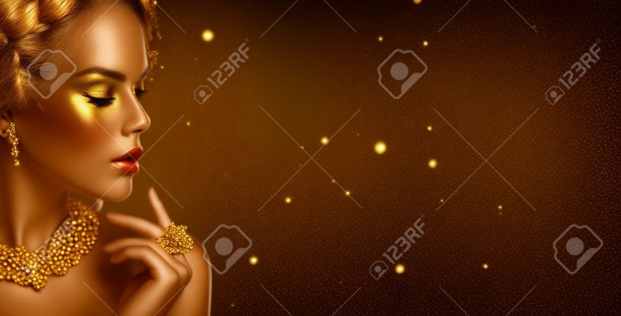 Mulher dourada. Menina modelo de beleza com maquiagem dourada, cabelo e jóias no fundo preto