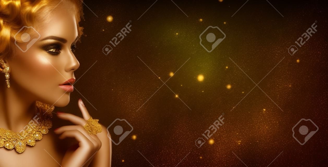 Gouden vrouw. Schoonheid model meisje met gouden make-up, haar en sieraden op zwarte achtergrond