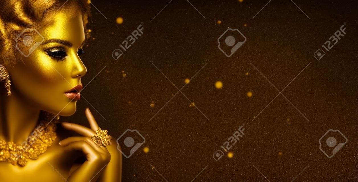 Mujer de oro. Chica de modelo de moda de belleza con maquillaje dorado, cabello y joyas sobre fondo negro