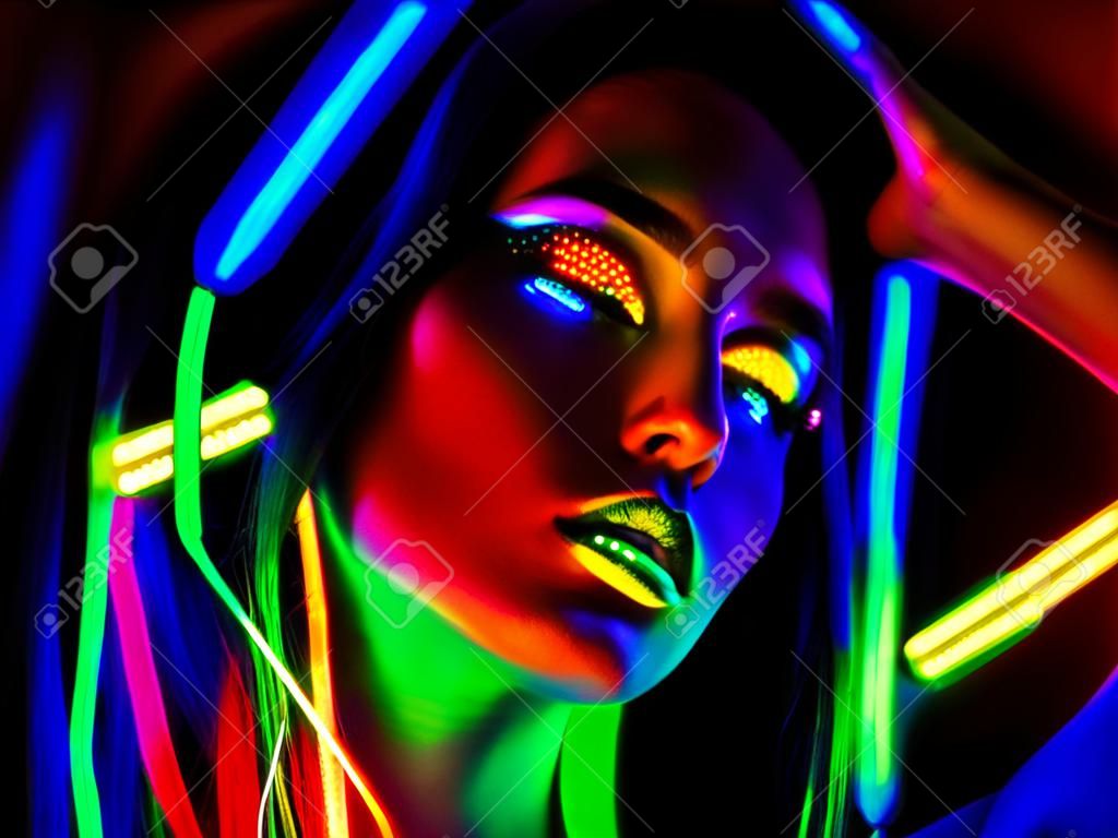 Mujer modelo de moda en luz de neón. Retrato de muchacha hermosa modelo con maquillaje fluorescente colorido