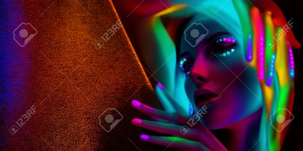 Женщина фотомодели в неоновом свете, портрет красивой модельной девушки с флуоресцентным макияжем, боди-арт дизайн в ультрафиолете, раскрашенное лицо, красочный макияж, на черном фоне