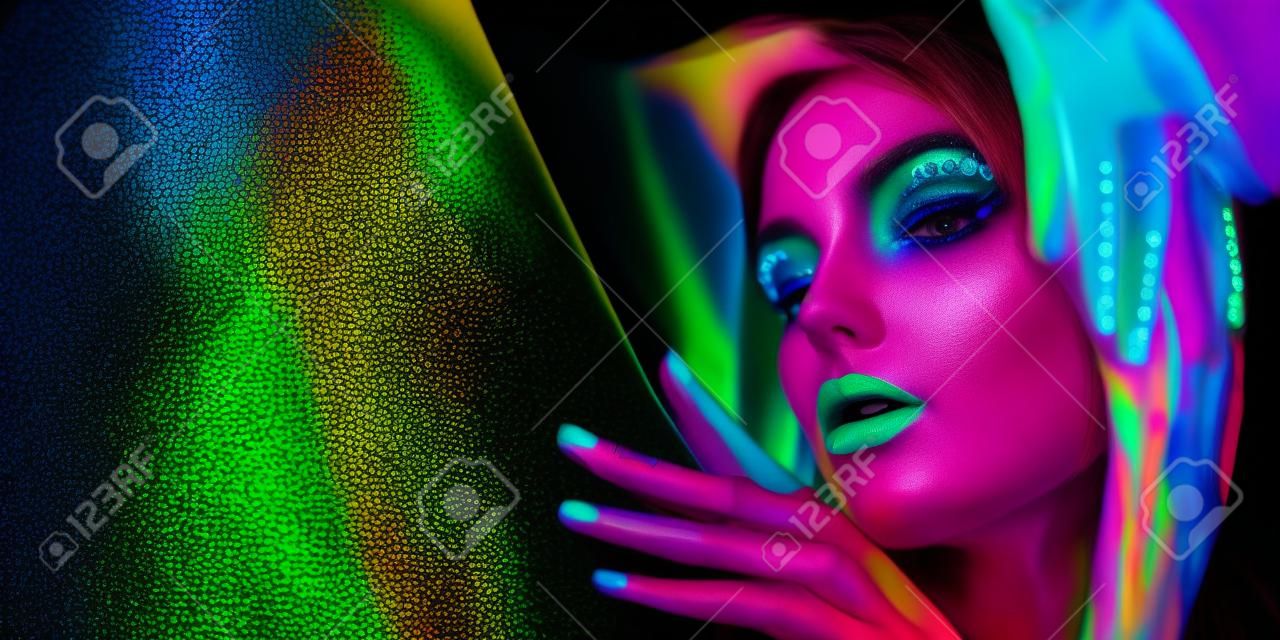 Женщина фотомодели в неоновом свете, портрет красивой модельной девушки с флуоресцентным макияжем, боди-арт дизайн в ультрафиолете, раскрашенное лицо, красочный макияж, на черном фоне