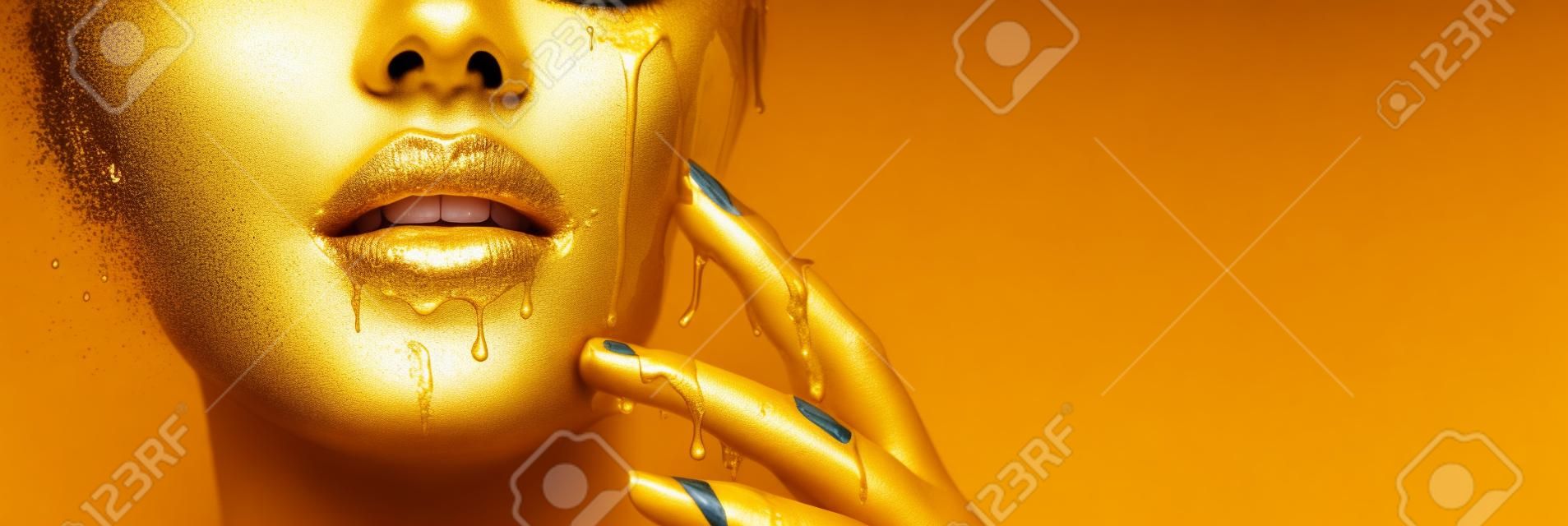 Manchas de tinta dourada goteja dos lábios do rosto e da mão, gotas líquidas douradas na boca da menina modelo bonita, maquiagem abstrata criativa.