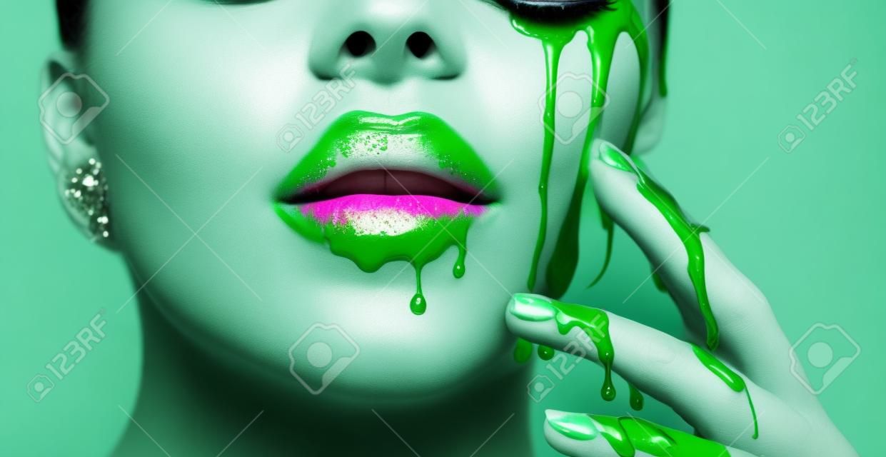 Smugi kapie z ust i dłoni, zielony płyn spada na usta pięknej modelki, kreatywny abstrakcyjny makijaż. piękna twarz kobiety