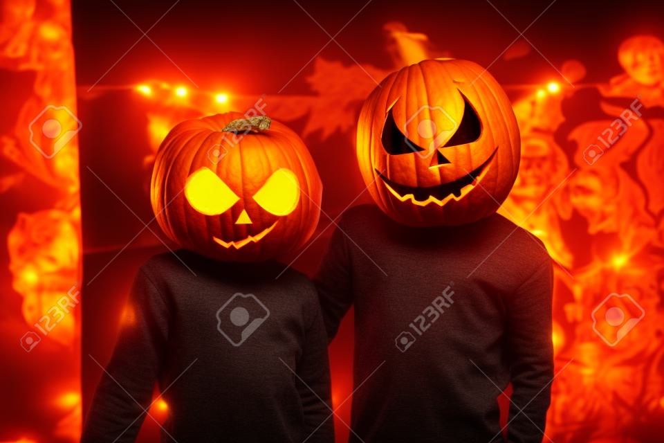 Niño y niña de halloween con calabazas en la cabeza