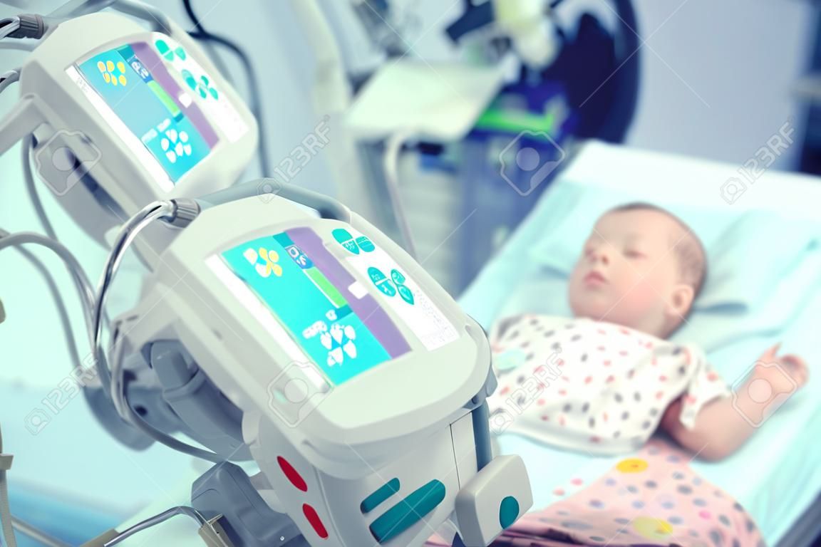 Newborn baby on the bed surrounded by the equipment in the intensive care unit of children's hospital.