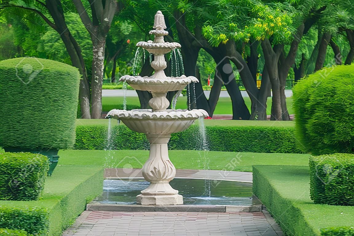 Watering fountain in public park with green natural background.
