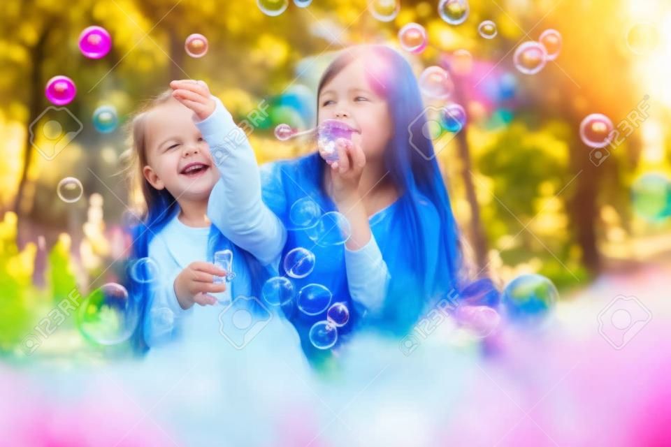 Heureuse mère et fille soufflant des bulles dans le parc
