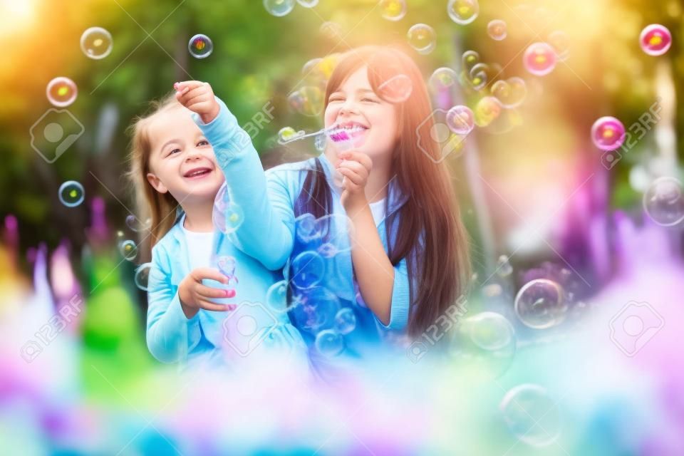 Heureuse mère et fille soufflant des bulles dans le parc