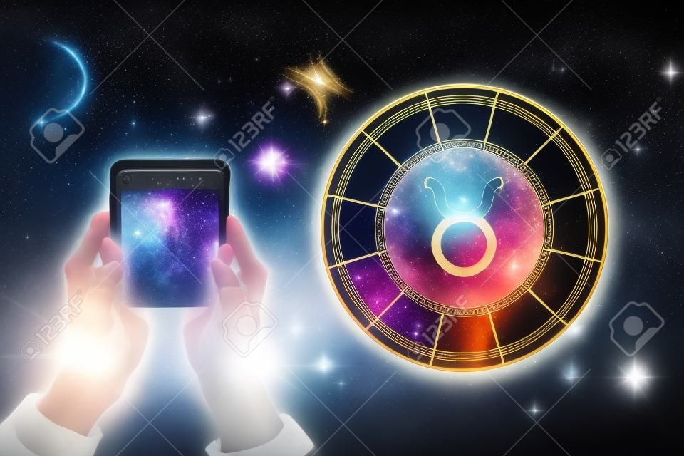 Weibliche Hände halten ein Telefon und einen astrologischen Kreis mit dem Sternzeichen Stier vor dem Hintergrund des Sternenhimmels. Horoskop-App.