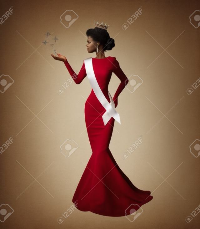 anmutige Silhouette einer schönen Frau in einer Krone, einem Pulloverband und einem langen Kleid bei einem Schönheitswettbewerb