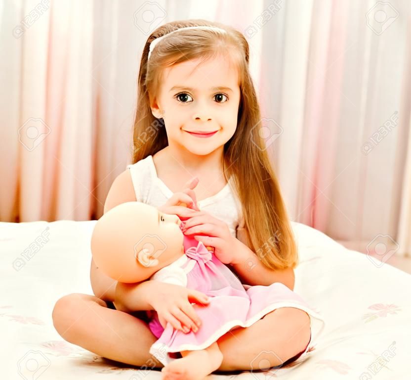 Cute smiling little girl playing with a doll at home