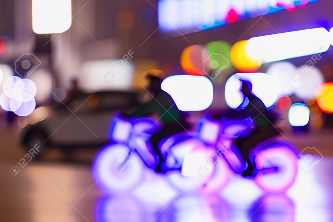 Schattenbilder des Reitens von Radfahrern im Verkehr auf Nachtstadt, helles bokeh, Zusammenfassung, Bewegungsunschärfe, violetter Hintergrund