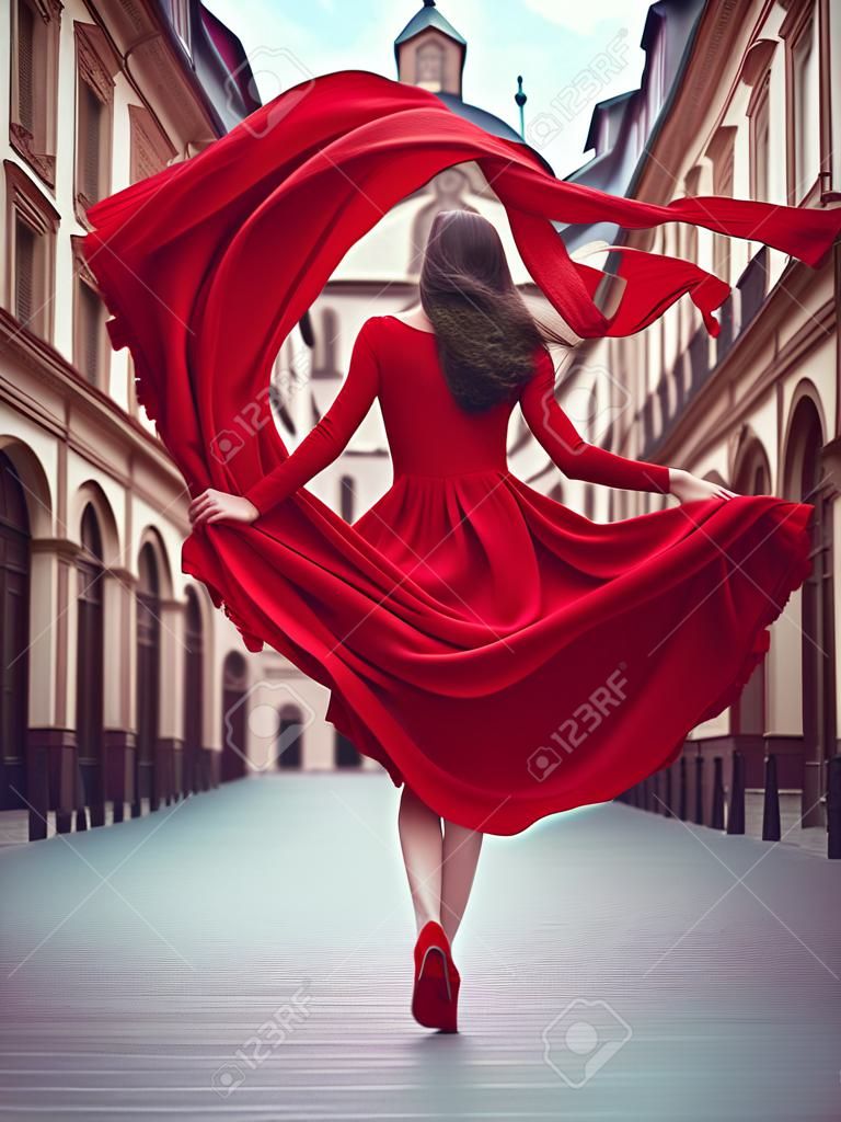 Superbe femme une belle robe rouge, mannequin au milieu d'une place vide de la vieille ville, vue de l'arrière, illustration générative ai