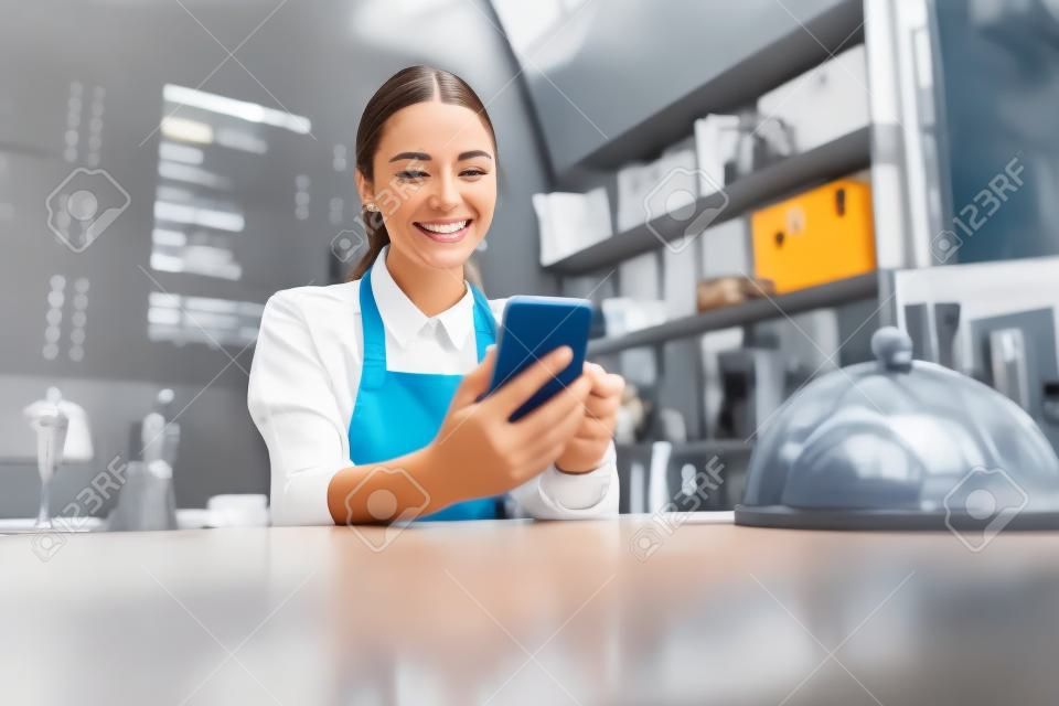 Happy smiling woman in uniform looking at the screen cell phone