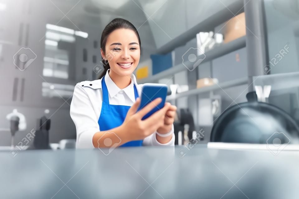 Happy smiling woman in uniform looking at the screen cell phone